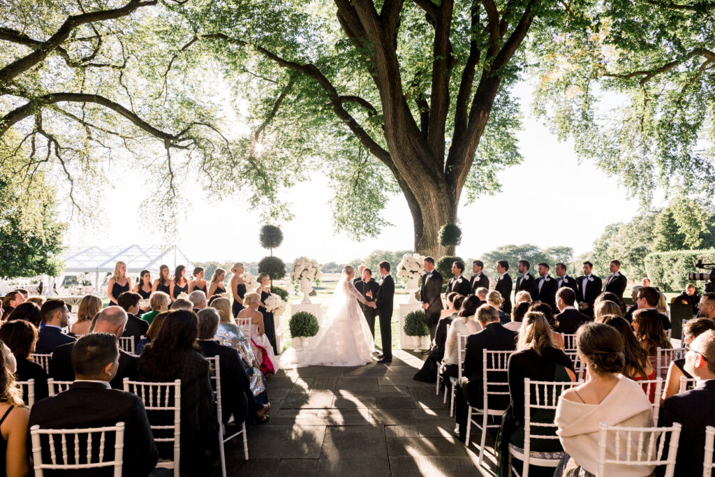 Bride and groom exchanging vows outside under a tree at the Onwentsia Club