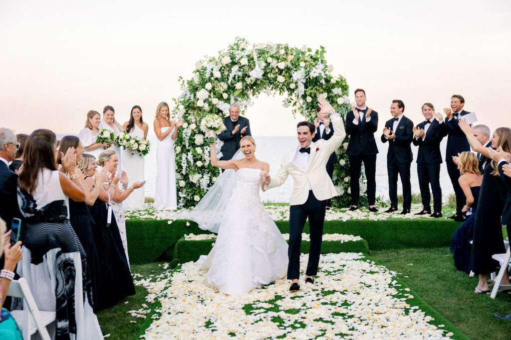 Bride and groom pumping fists walking down the aisle outside at the Shoreacres Country Club