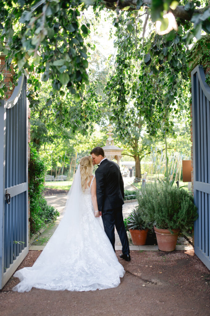 Bride and groom kissing between a gate under a tree at the Chicago Botanic Garden