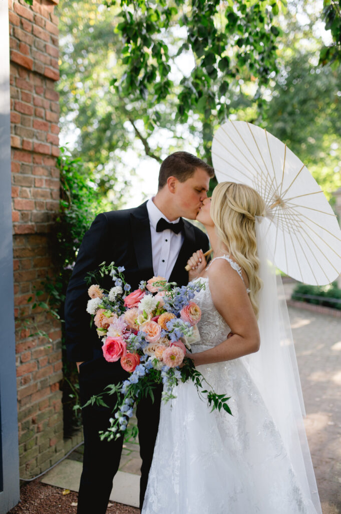 Bride and groom kissing under a parasol