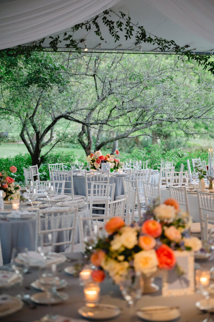 Tented reception venue with orange and white flower centerpieces at the Chicago Botanic Garden